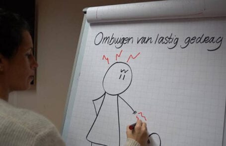 Vrouw schrijft op whitepaper ‘ombuigen van lastig gedrag’ met een gefrustreerd getekend poppetje eronder