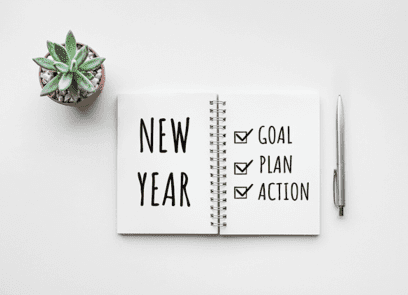 Open notitieboekje met op linkerpagina de tekst ‘New Year’, op rechterpagina drie aangevinkte hokjes met de woorden ‘goal, plan, action’.